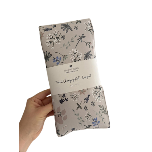 Floral-patterned changing mat held by a hand with 'Ralphie Bear' branding.