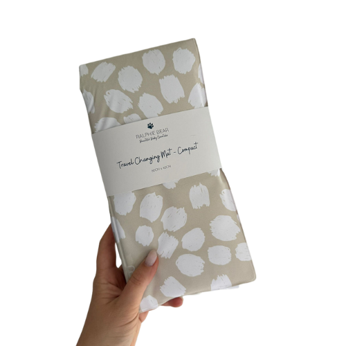 Travel changing mat with white patterns held by a hand on a white background