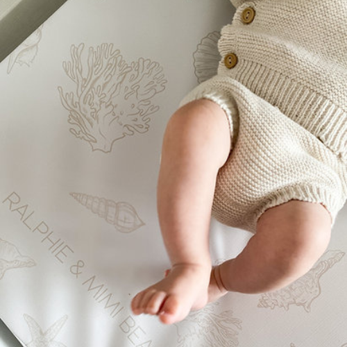 Baby's legs in knitted shorts on a branded mat