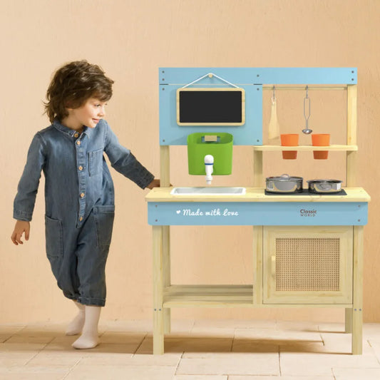 Child playing with a toy kitchen set against a beige wall.