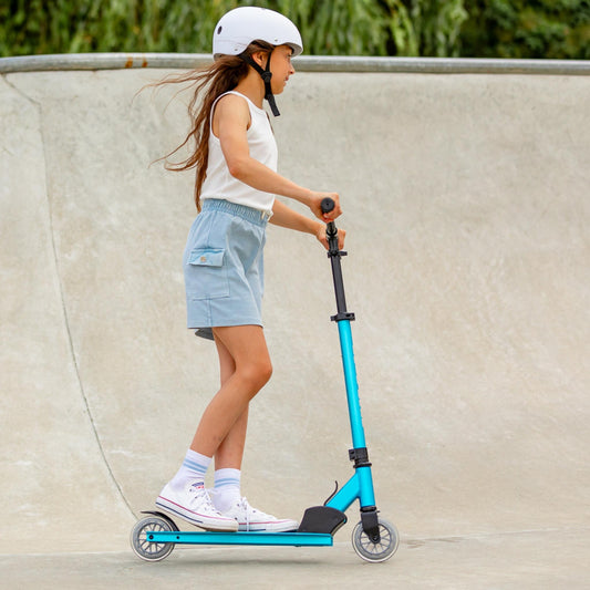 Child riding a blue scooter at a skate park