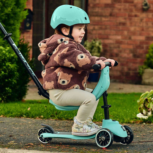 Child on sit on scooter wearing helmet 