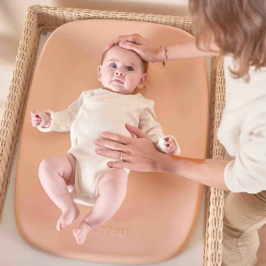 Baby lying on a changing pad with a person adjusting the baby's head