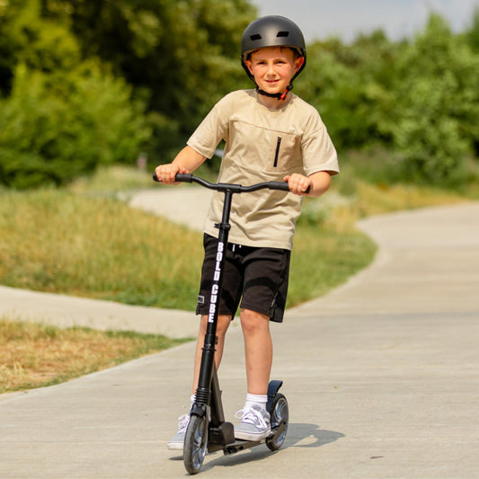 Child riding a scooter on a path with greenery in the background