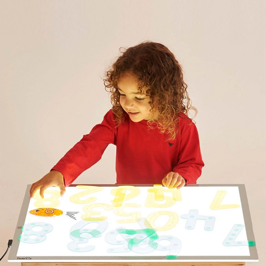 Child playing with a light-up panel displaying letters and numbers