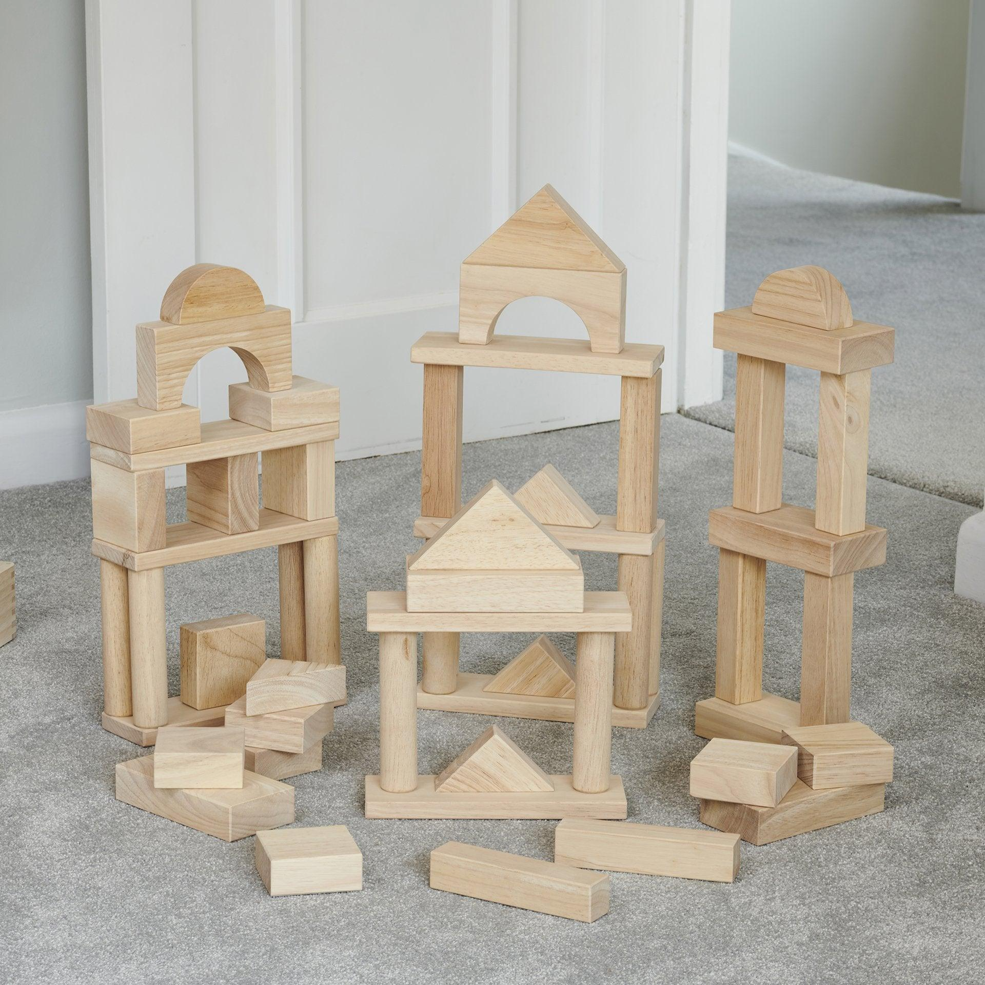 Set of wooden building blocks on a gray floor with a white wall background