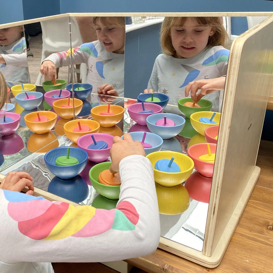 Children playing with colorful bowls and sticks reflecting off the mirrors