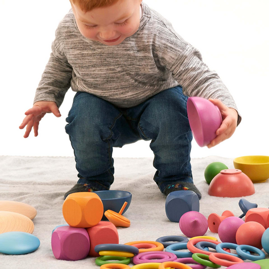 Child playing with colourful wooden toys on a light surface