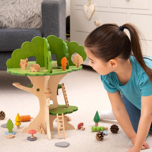 Child playing with a wooden treehouse toy set on a carpeted floor.