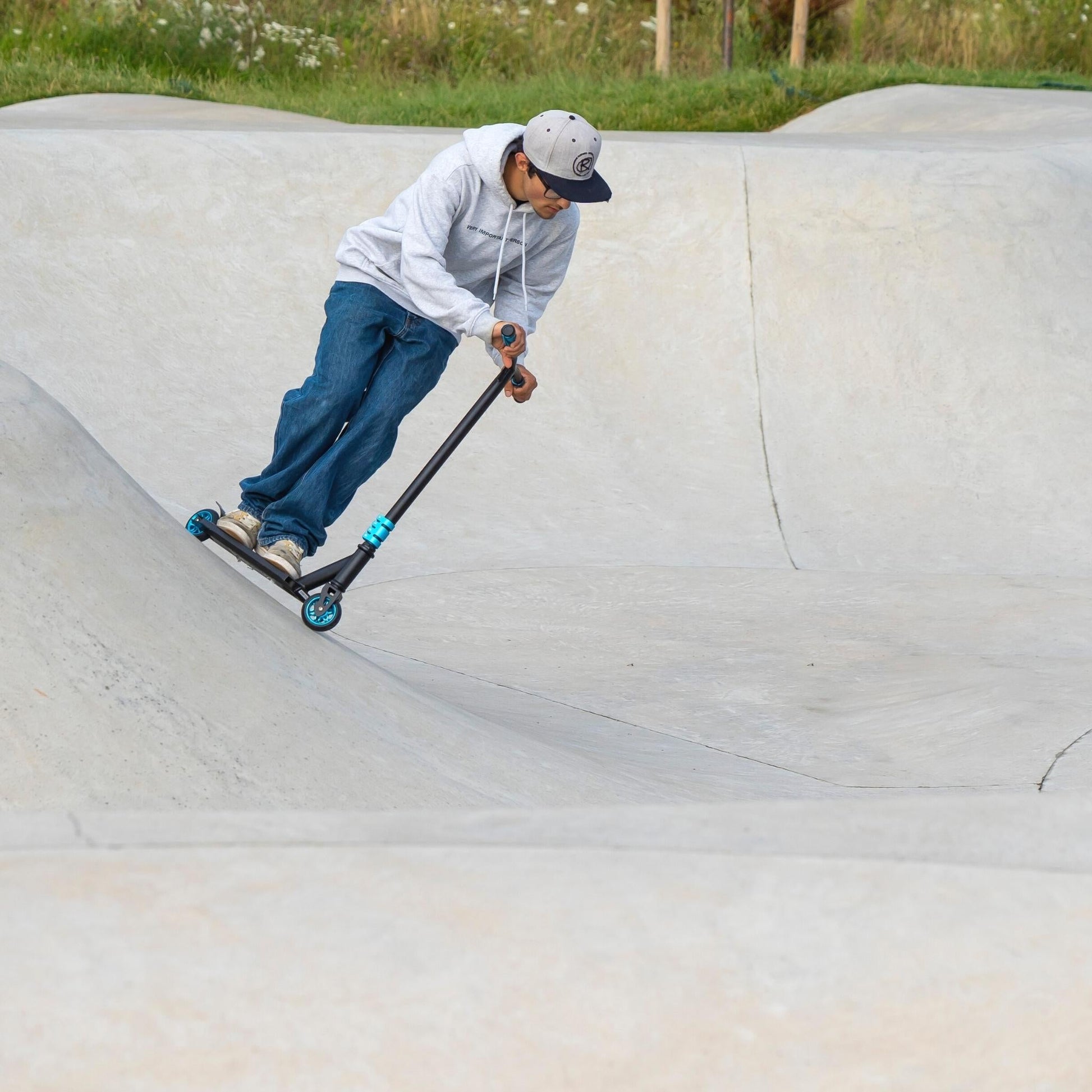 Person riding a scooter on a concrete bowl at a skate park