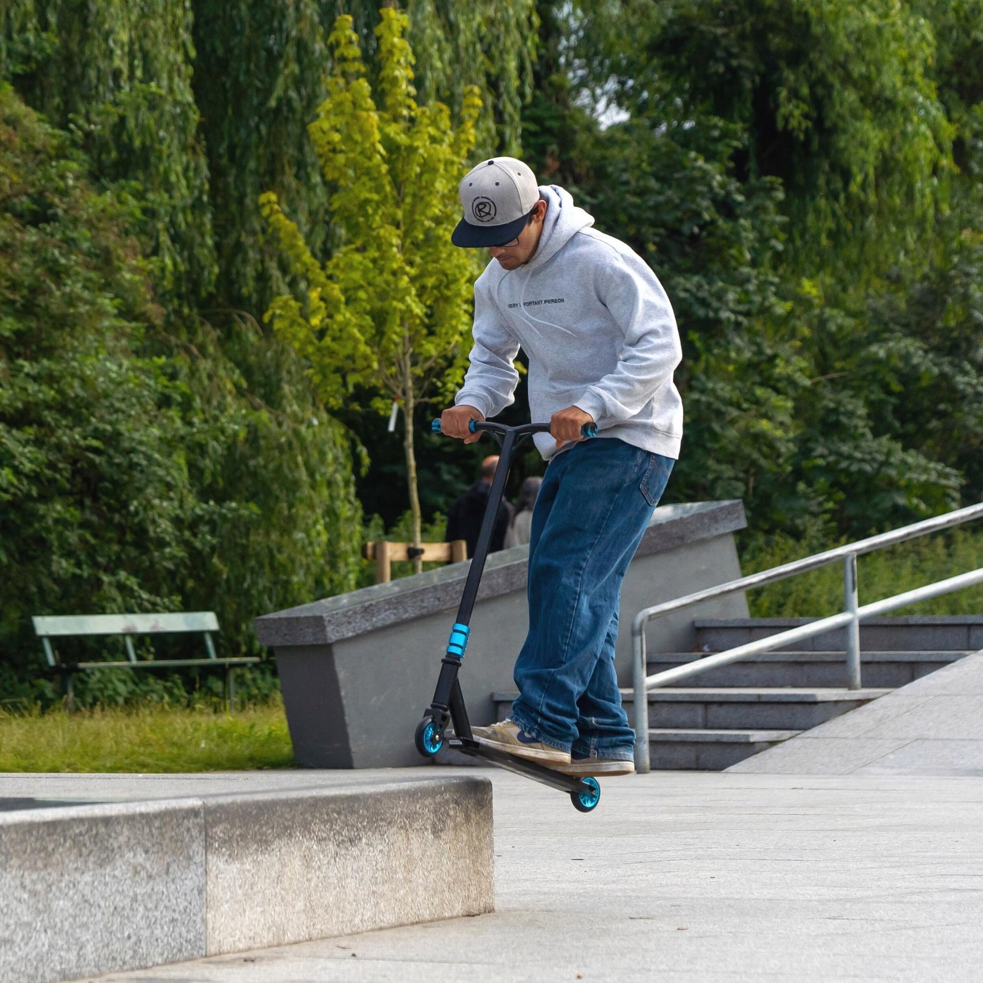 Person riding a scooter on a concrete path with greenery in the background