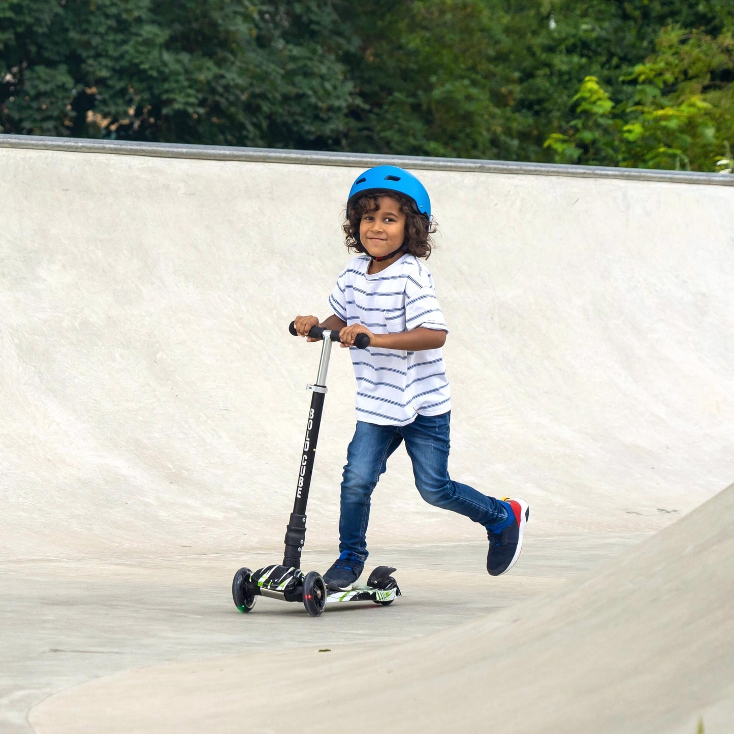Child riding a scooter with a helmet on a concrete surface.