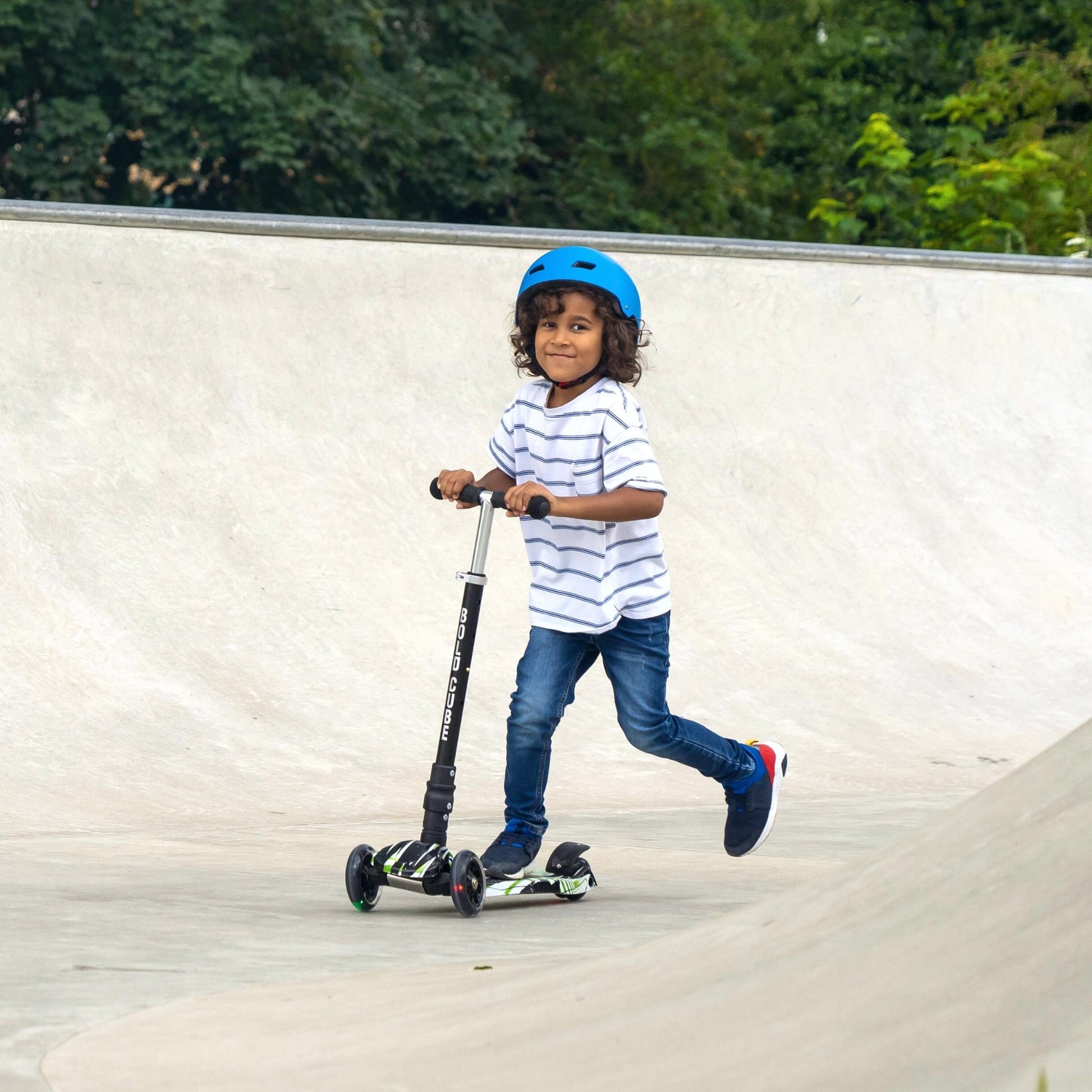 Child riding a scooter with a helmet on a concrete surface.