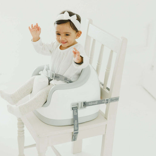 Child in a high chair with a safety harness on a white background