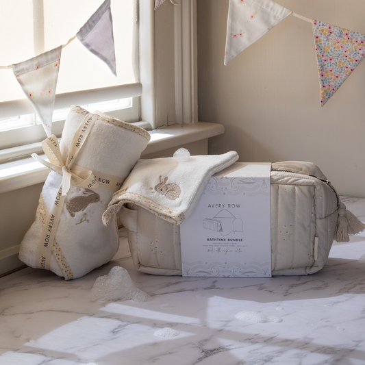 Baby shower gift set with a baby blanket and pillow on a marble surface, decorated with bunting.
