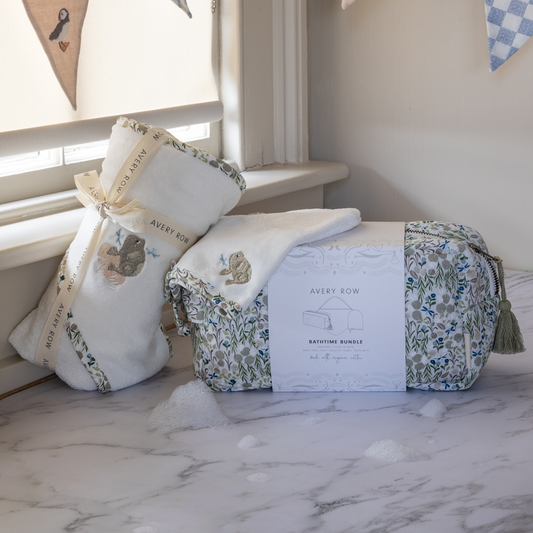 Baby gift set with crib sheet, pillow, and bag on a marble surface.