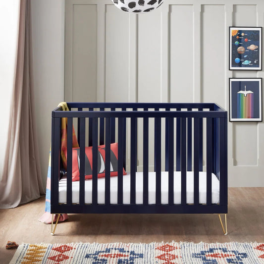Navy crib in a room with colorful rug and wall art