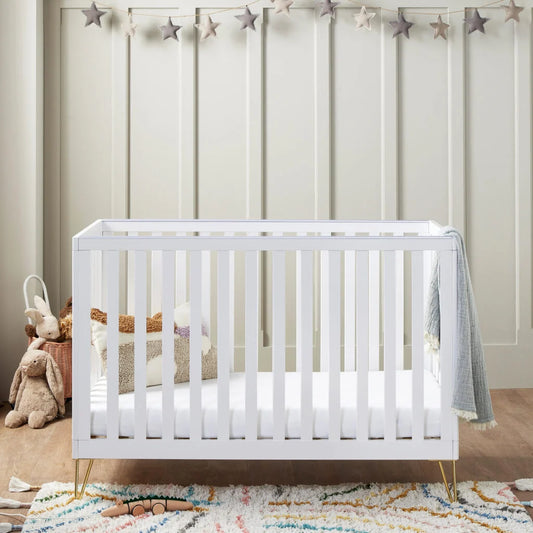 White crib in a nursery with toys and a star banner on the wall.
