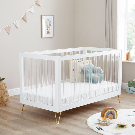 Kimi Cot Bed with a Acrylic spindles in a bedroom with rug and toys.