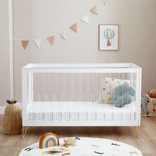 Kimi Cot Bed with a Acrylic spindles in a bedroom with rug and toys.