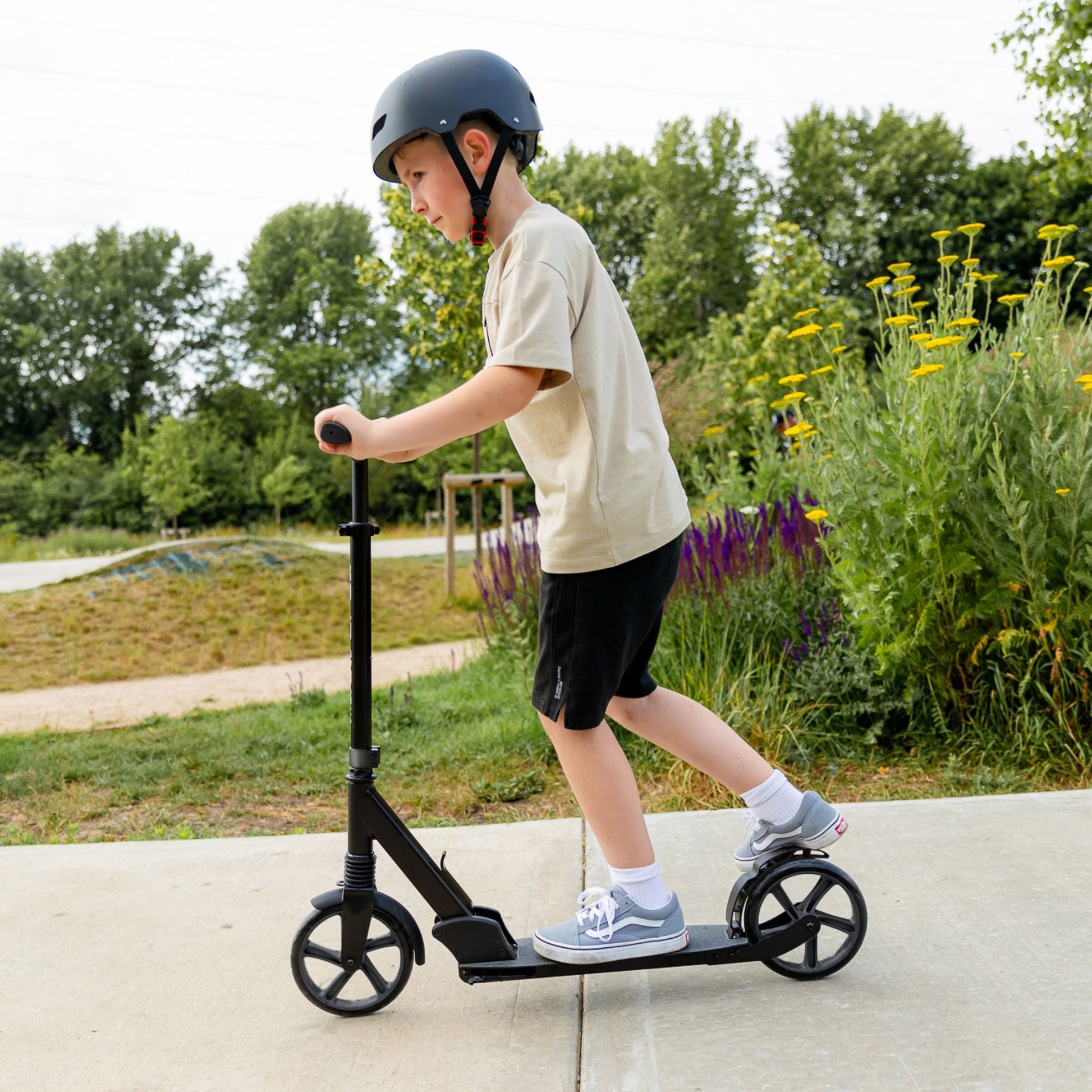 Child riding a scooter outdoors with greenery in the background