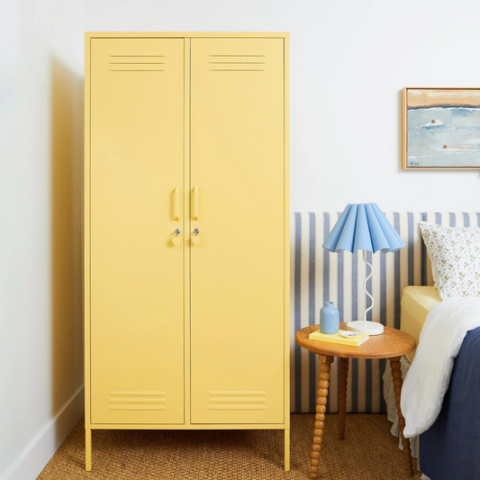 Yellow locker-style cabinet in a room with a striped wall and a lamp.