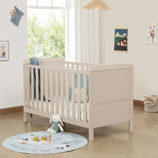 Cashmere cot in a bright nursery with toys and a rug on the floor.