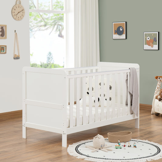 White cot in a nursery with toys and decor