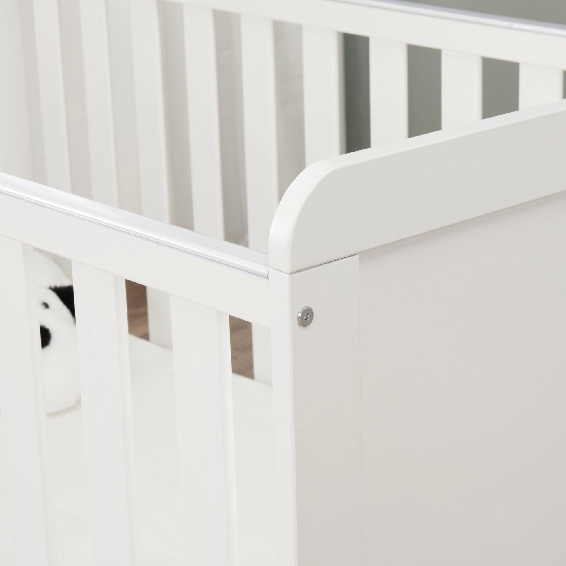Close-up of a white cot with a teething rail with a neutral background