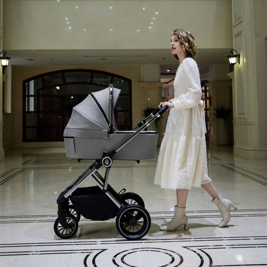Woman in a white dress pushing a baby stroller in an elegant hallway.