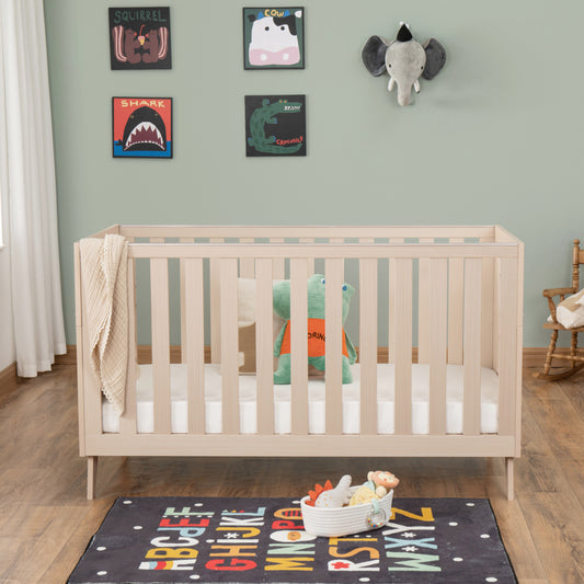 Nursery room with a wooden cot, colourful rug, and wall decorations.