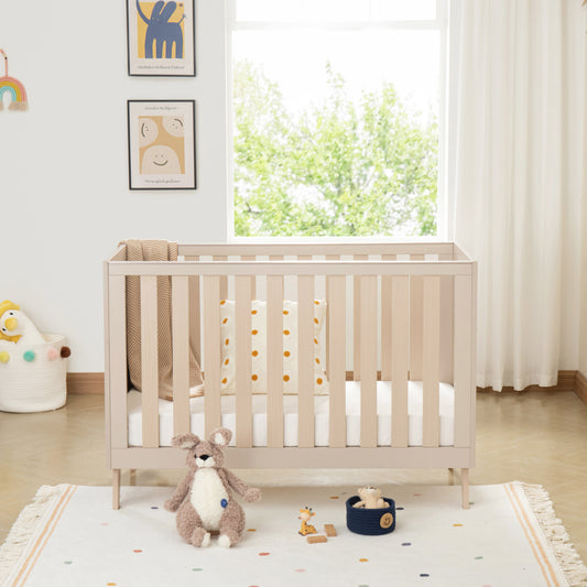 Nursery room with a crib, toys, and a window with white curtains.