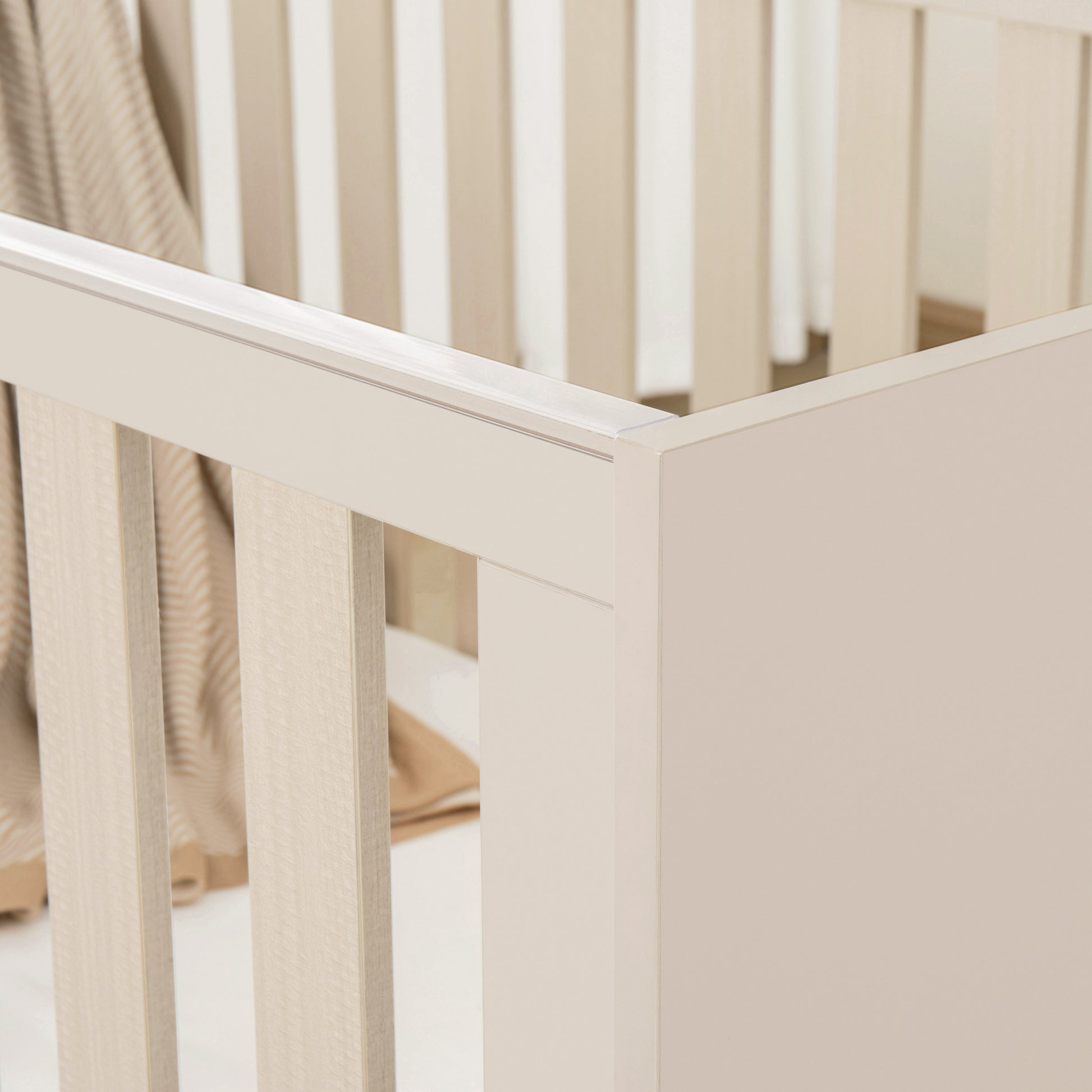Beige cot with a soft beige blanket inside, on a light background