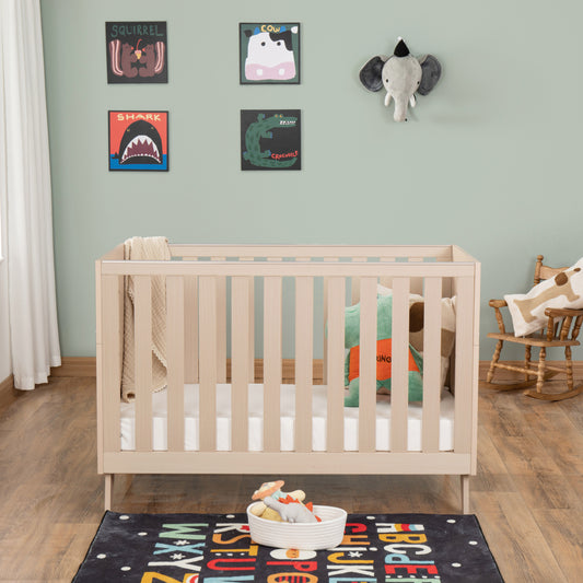 Nursery room with a cot, colourful rug, and wall art.