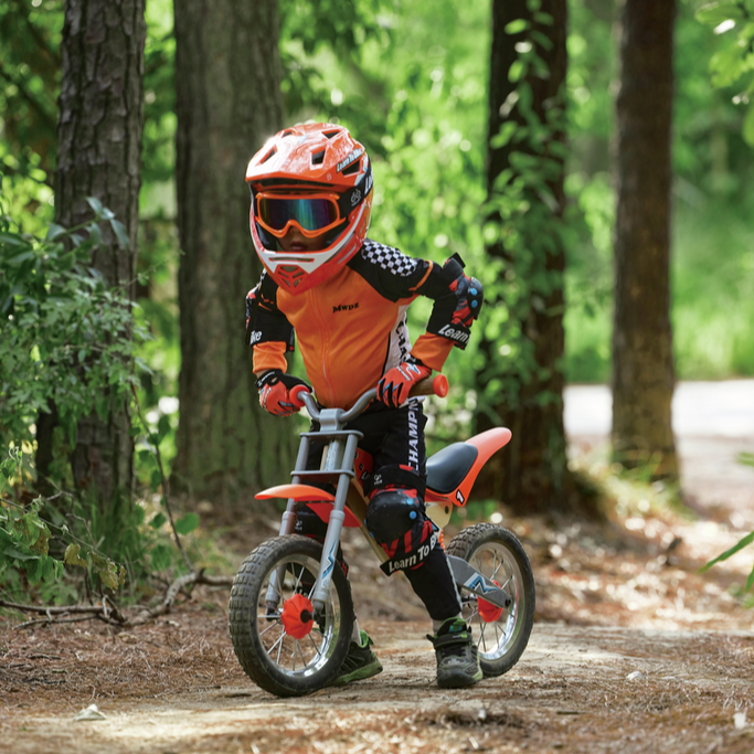 Child riding a balance bike in a forest setting