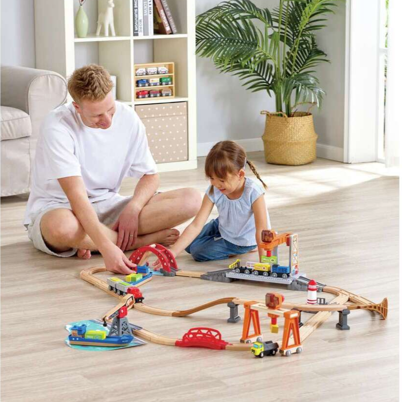 A child playing with a train set with a male adult 