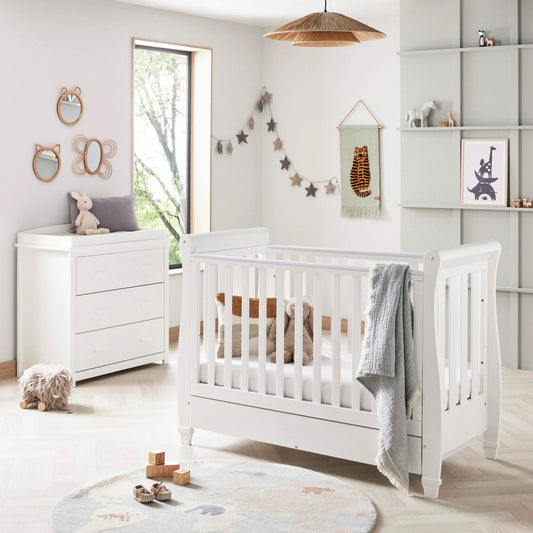 Nursery room with a white crib, dresser, and decorative elements.