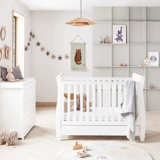 Nursery room with a white crib, dresser, and decorative elements.