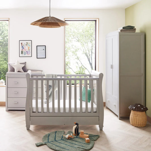 Nursery room with a gray crib, wardrobe, and toys on a wooden floor.