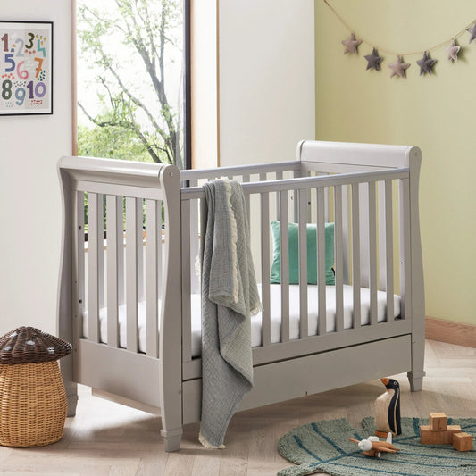 White crib in a room with toys and a window