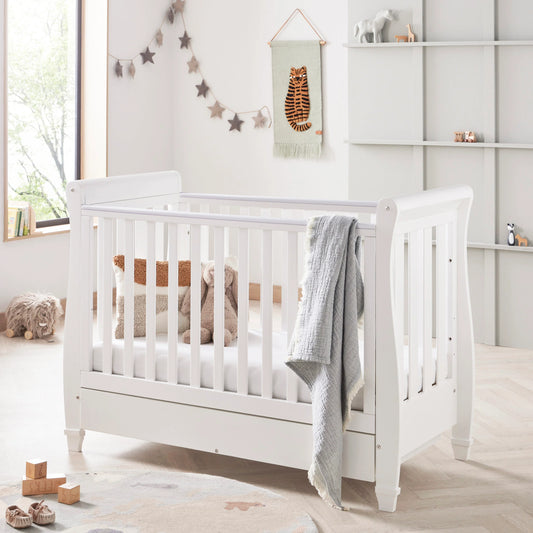 White crib in a nursery with decorative elements and toys.