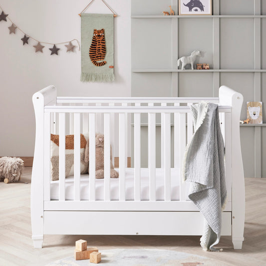 White crib in a nursery with toys and decor