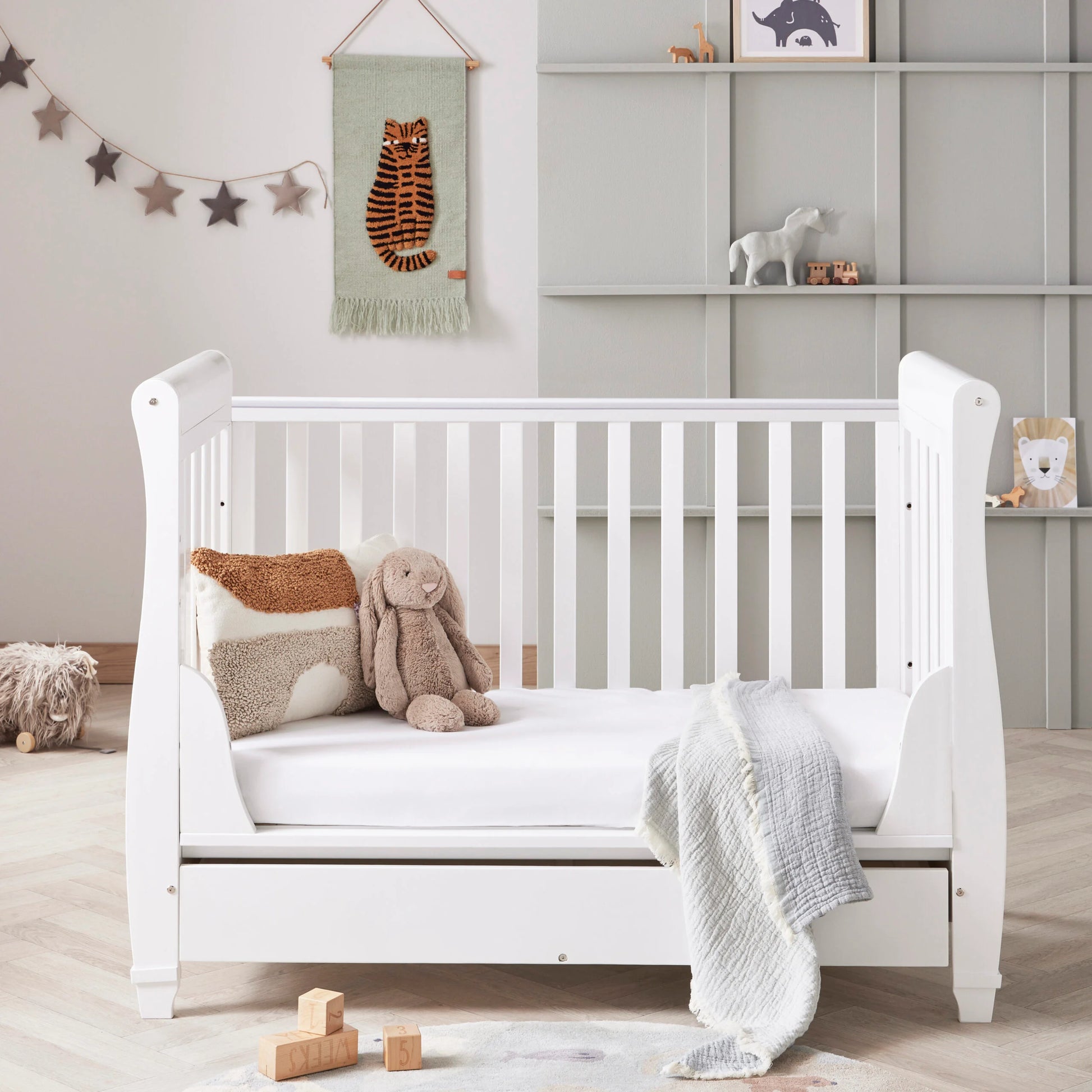 White crib in a nursery with toys and decorations