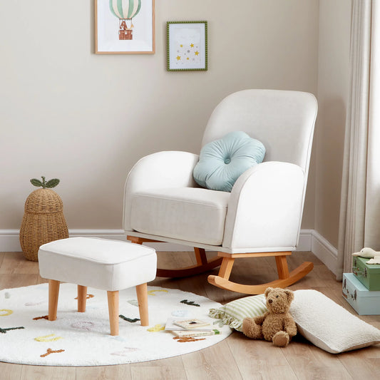 White rocking chair with a blue pillow in a child-friendly room with toys and a rug.