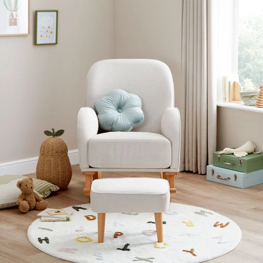 White armchair with a blue cushion in a child's room with toys and a rug.