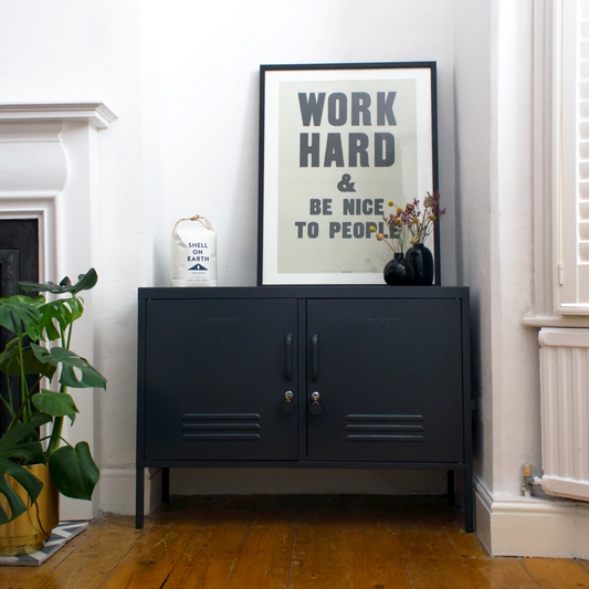 Navy blue cabinet with a framed print titled 'Work Hard & Be Nice to People' in a room with wooden flooring and white walls.