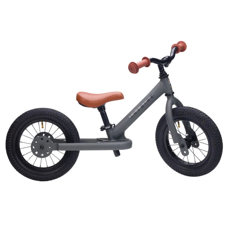 Children's balance bike with gray frame and brown seat on a white background