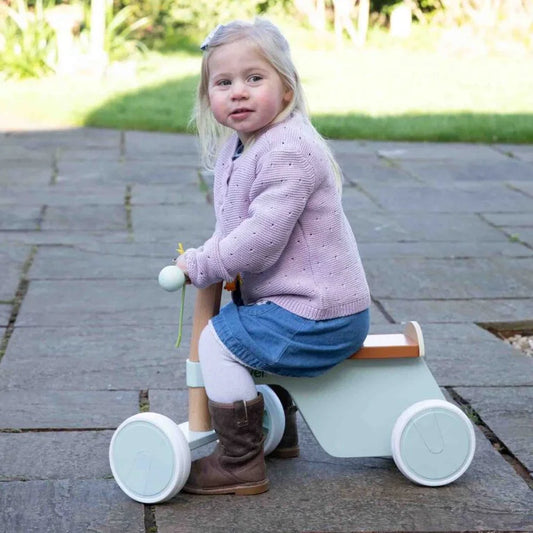 Child riding a light blue tricycle outdoors on a paved surface.