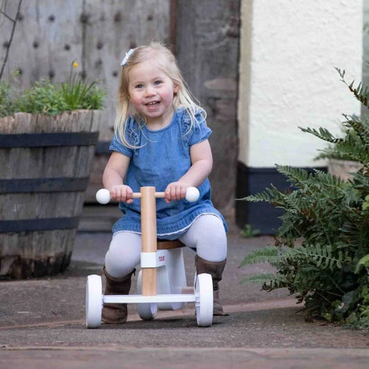 Young girl riding a wooden tricycle outdoors