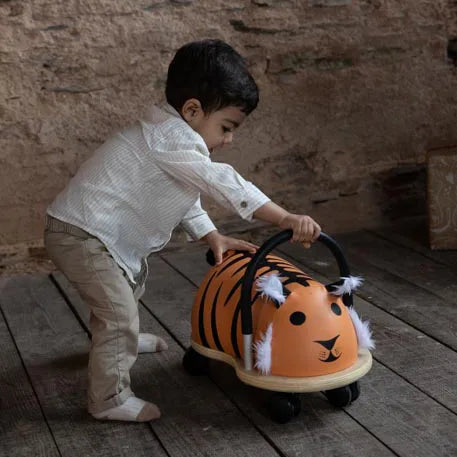 Child playing with a tiger-themed toy car on wooden flooring.